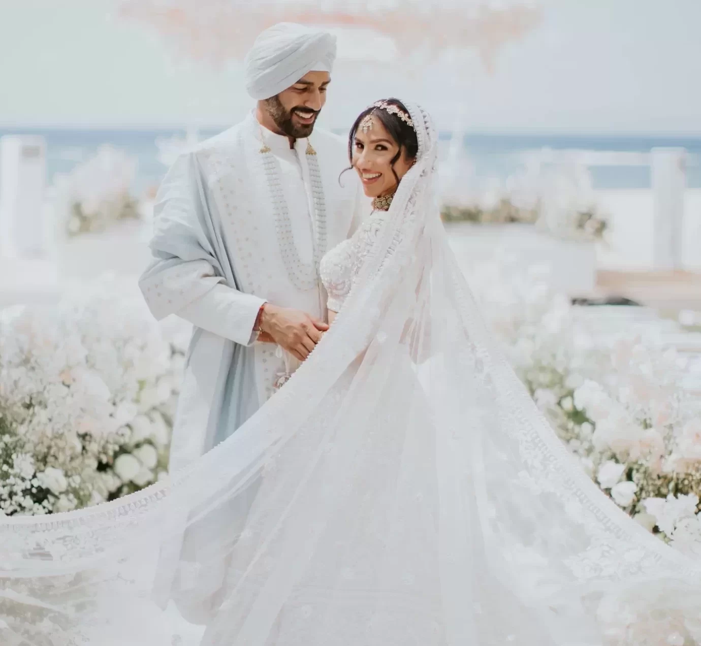 Bride and groom in coordinated white wedding outfits during an elegant outdoor ceremony.