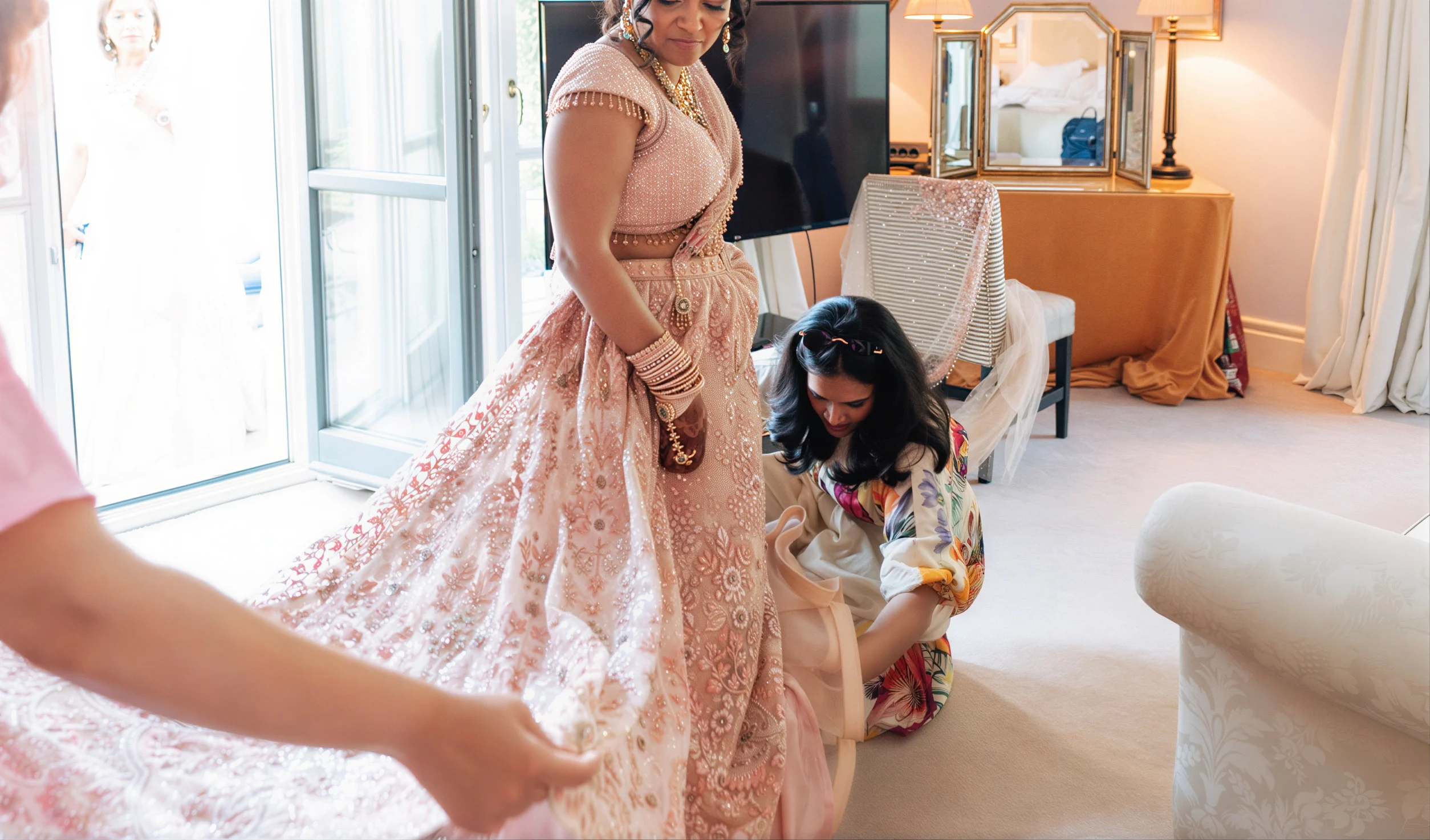 Bride receiving final outfit adjustments during wedding day bridal styling preparation