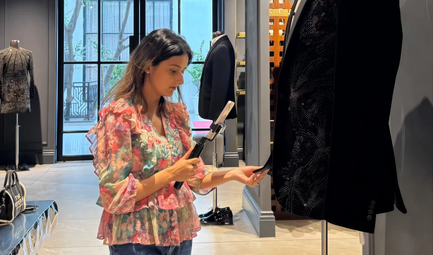 Stylist inspecting garment fabric and documenting details during wedding outfit fitting and quality check.