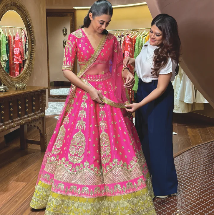 Personal stylist assisting a client with a pink bridal lehenga during a personal shopping session